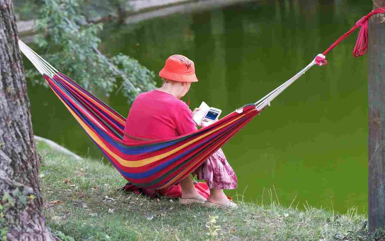 Woman relaxing in a hammock outdoors near water, enjoying a peaceful and stress-free setting.